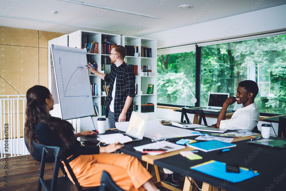 Man drawing diagram on board for colleagues Man drawing diagram on board for colleagues