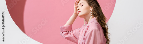 panoramic shot of beautiful girl touching hair on white and pink