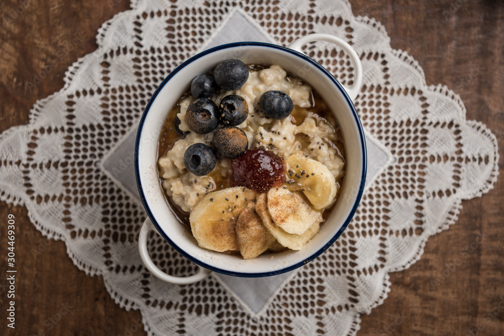 Porridge close-up. Ingredients: oat flakes, banana, blueberries, chia, cinnamon, maple syrup and strawberry jam. Horizontal. Top view. Middle Porridge close-up. Ingredients: oat flakes, banana, blueberries, chia, cinnamon, maple syrup and strawberry jam. Horizontal. Top view. Middle