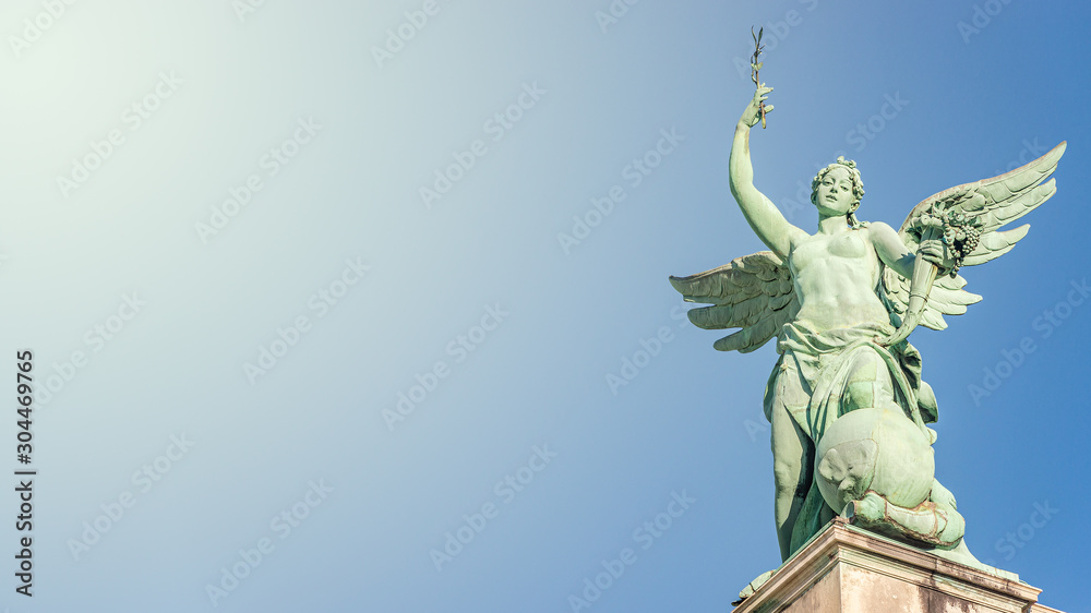 Obraz premium Banner with top roof statue of sensual Renaissance Era angel with wings in front of blue sky with direct light in Vienna, Austria, and copy space, details, closeup