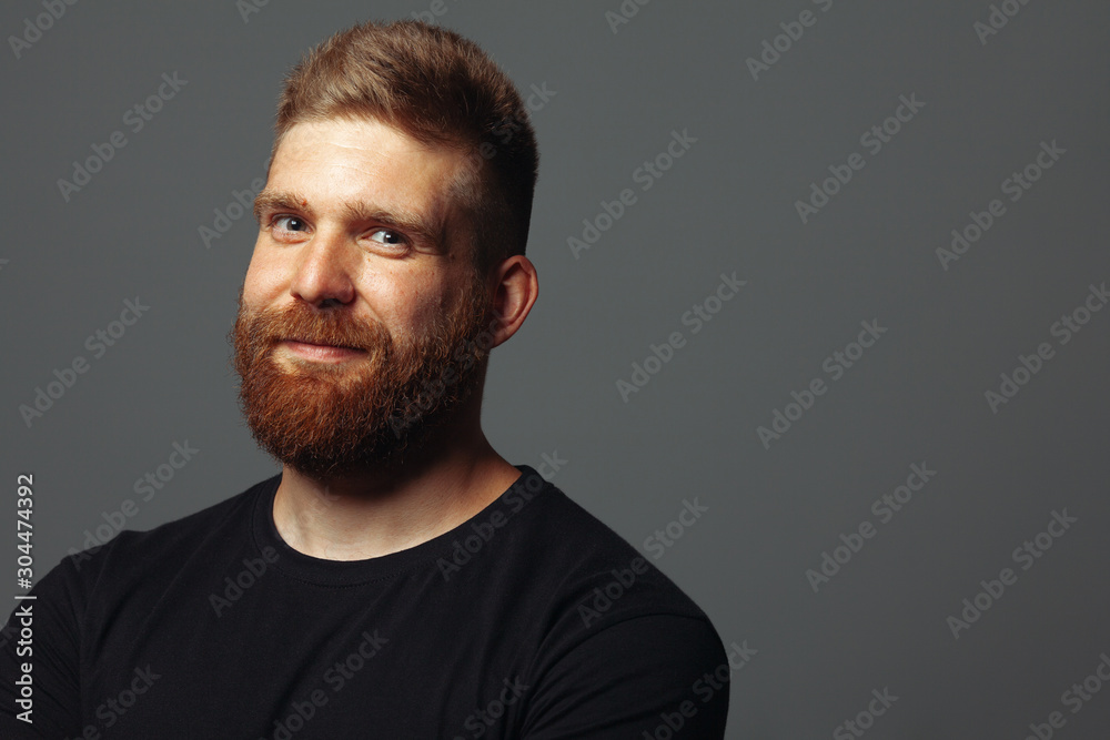 Fabulous at any age. Close up portrait of charismatic muscular 30-year-old man standing over dark gray background. Perfect haircut. Rocker, biker, hipster style. Copy-space. Studio shot