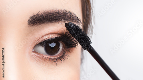 Close up beside applying mascara brush on eyelash. Applying cosmetic make up eyelash Extensions. Asian eye make up cosmetics. photo