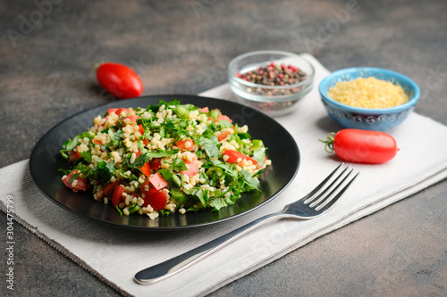 Traditional oriental salad Tabbouleh with bulgur and parsley on a dark background.