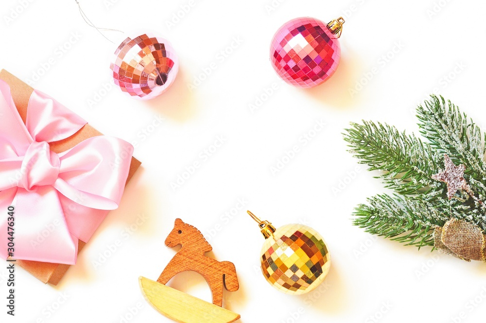 Flat lay photography New Year present, elegant and classy home decoration. Mockup. Wrapped gift box with pink satin bow ribbon, toy wooden horse, red and yellow balls and Christmas tree branch