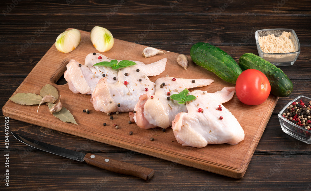 Fresh raw chicken wings on a cutting board on rustic table Fresh raw chicken wings on a cutting board on rustic table