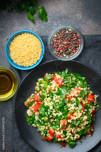 Traditional oriental salad Tabbouleh with bulgur and parsley on a dark background top view copy space.