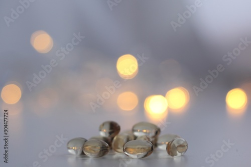 Closeup of vitamin D capsule with fairy lights in the background. Supplementation of vitamin D in winter. photo