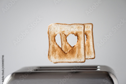 Two Heart shaped on roasted toasted bread in a toaster. Breakfast preparation on Valentine's Day. symbol sign of love. Concept