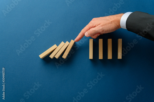 Cuadro en lienzo Collapsing dominos being stopped my a crisis business manager