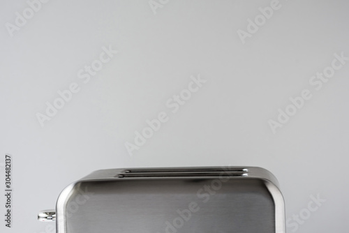 Old Fashioned stainless steel retro toaster on the gray background and white table.