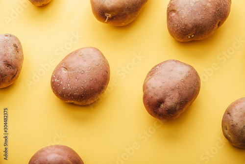 pattern of raw whole fresh potatoes on yellow background