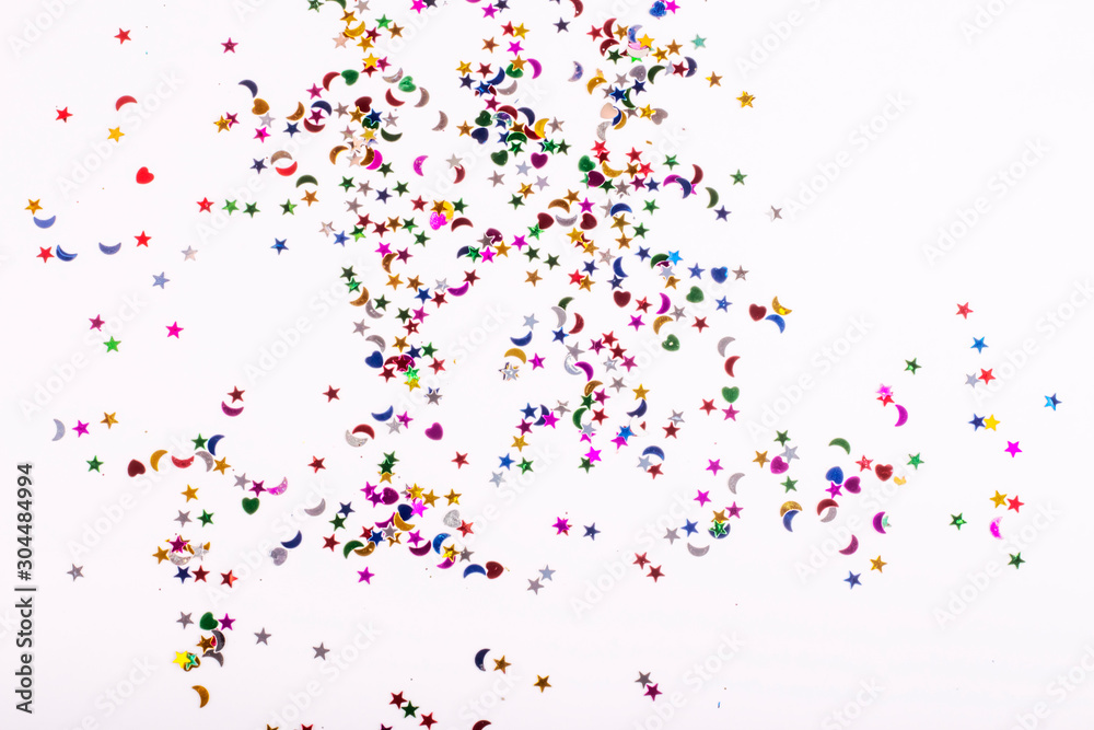 scattered colored sequins of various shapes on a white background