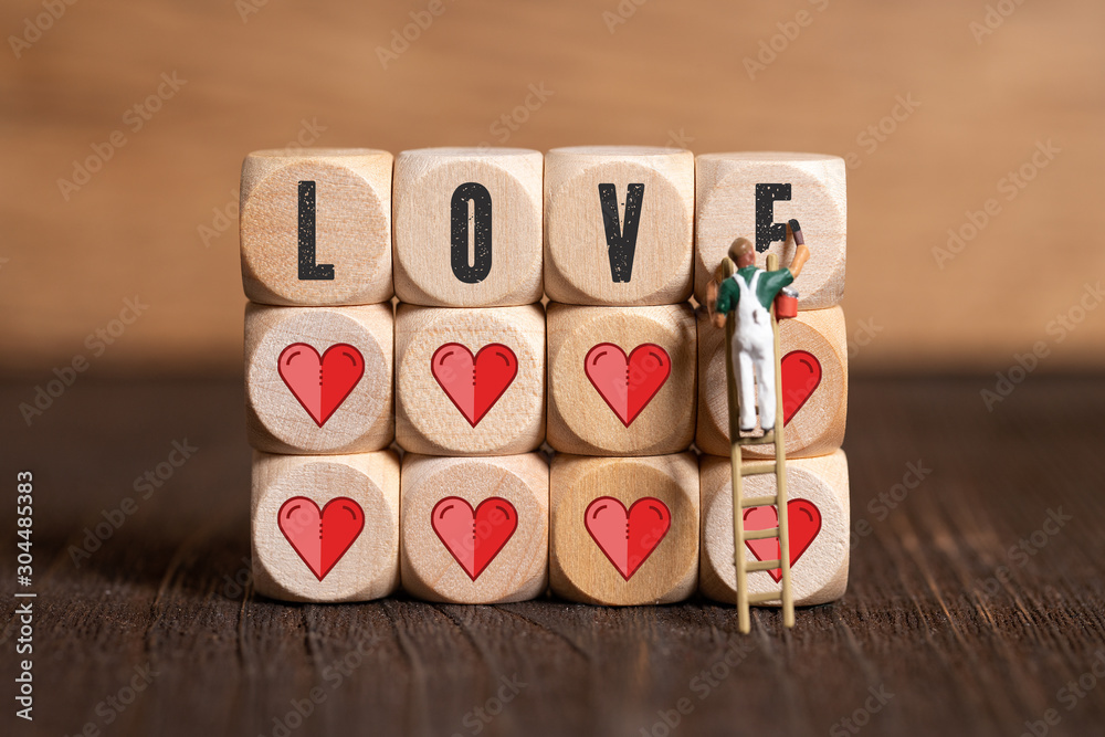 painter figure and wooden blocks with heart icons on wooden background