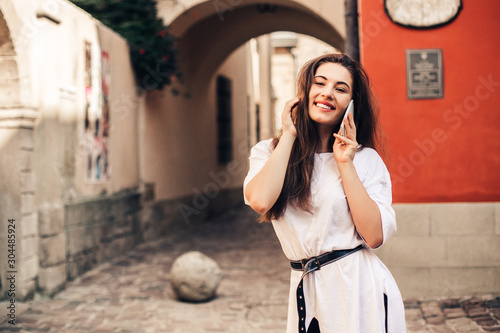 Beautiful woman traveler using phone walking on the old town street.