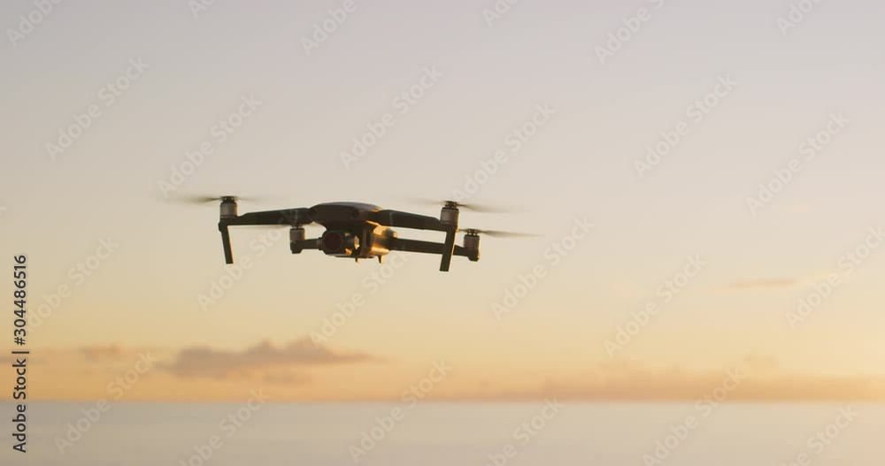 Orbiting view of an unstable quadcopter drone hovering in the air in slow motion at sunset Orbiting view of an unstable quadcopter drone hovering in the air in slow motion at sunset