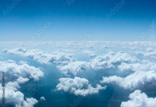 View from the window of the airliner on the small clouds above the ground
