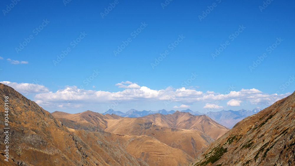 Brown and yellow slopes of the mountains with blue cloudy sky background
