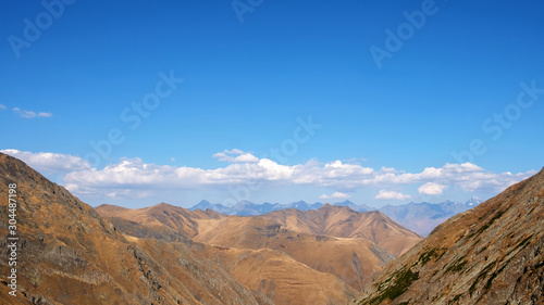 Brown and yellow slopes of the mountains with blue cloudy sky background