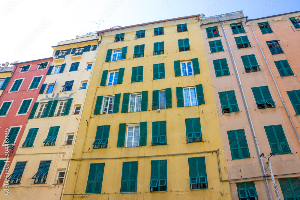 Facade of an old Italian building in old part of town, windows with shutters, old building in Genoa, Italy.