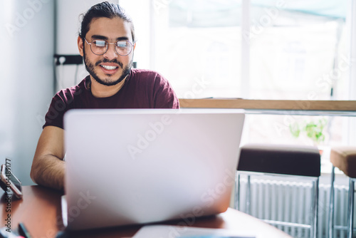 Smiling casual student using laptop
