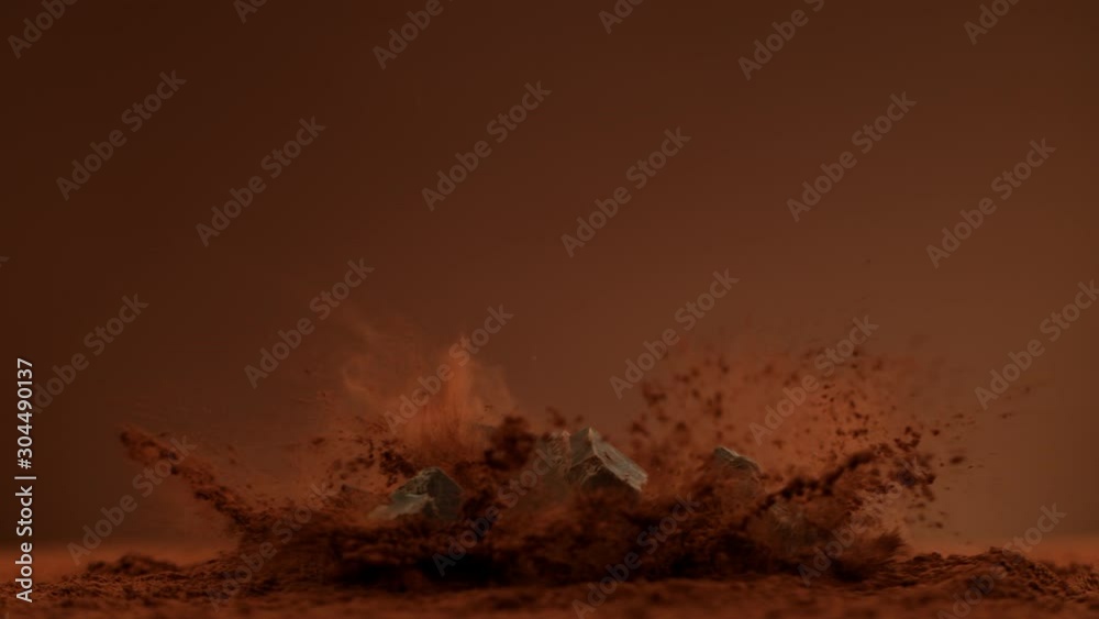 Super Slow Motion Shot of Raw Chocolate Chunks Falling into Cocoa Powder at 1000fps.