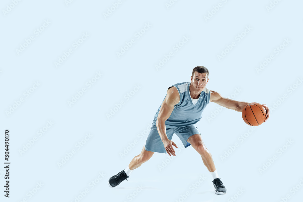 Passioned for. Young caucasian basketball player of team in action, motion in jump isolated on blue background. Concept of sport, movement, energy and dynamic, healthy lifestyle. Training, practicing.