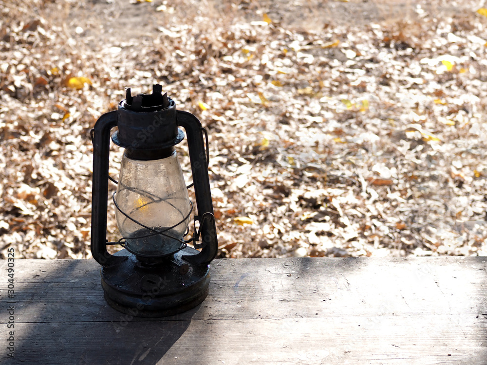 old oil lamp on a wooden bench in the autumn park