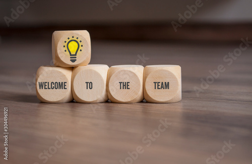 Cubes and dice on wooden background with the message welcome to the team © Stockwerk-Fotodesign