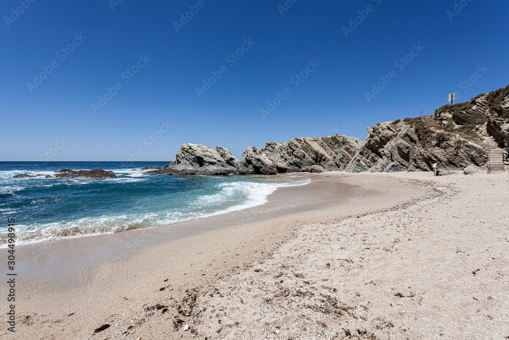 Praia protegida das ondas do oceano pelas rochas.