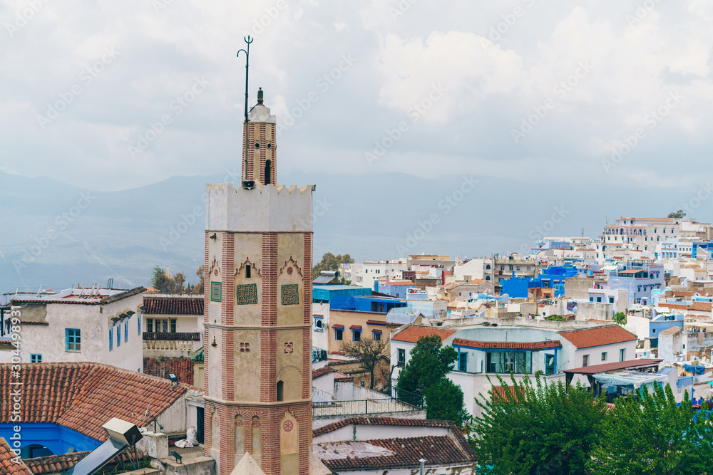 landscape. rooftops, a tower, and in the distance mountains in the fog. Morocco