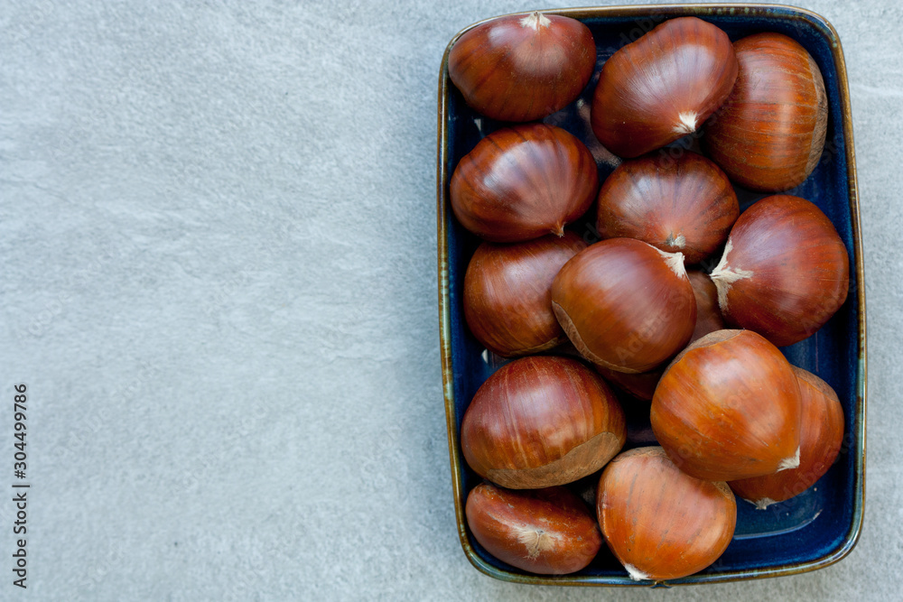 Obraz premium Edible chestnuts on a blue plate.