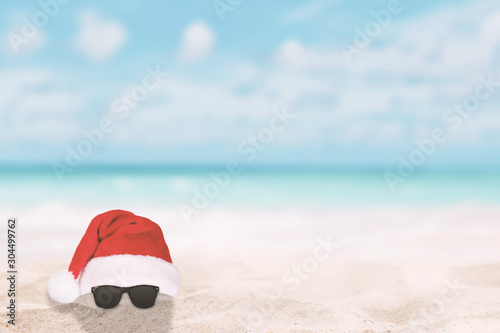 Santa Claus hat and sunglasses on a tropical beach. Christmas travel vacation in hot countries concept