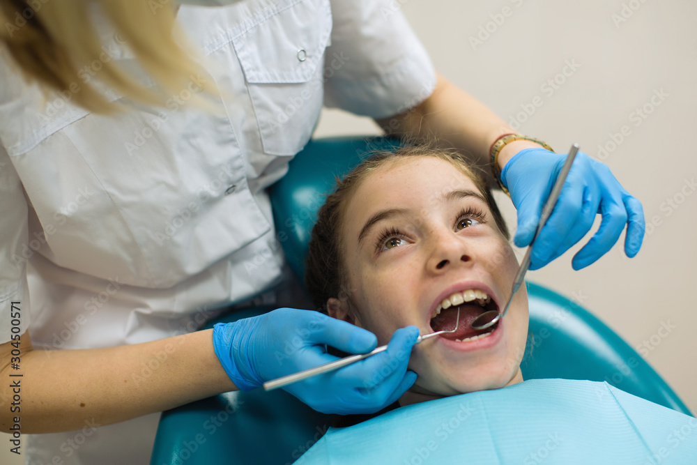 Dentist woman doing teeth checkup of teen girl in dental chair at clinic. Dentist woman doing teeth checkup of teen girl in dental chair at clinic.