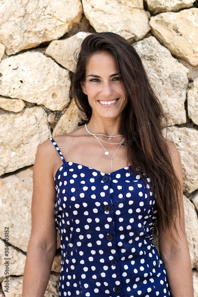 Beautiful hispanic woman in blue dress leaning on wall while looking camera Beautiful hispanic woman in blue dress leaning on wall while looking camera