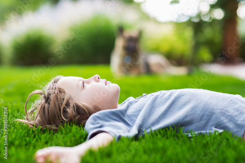 Side view of boy lying on green lawn looking up photo
