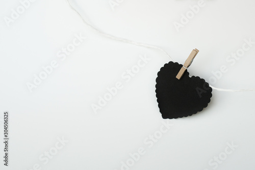 Black Heart Shape Hanging on String with Clothespin on White Background