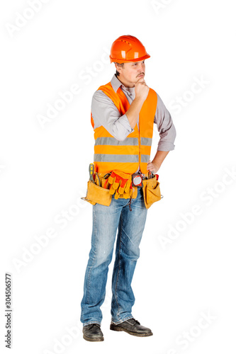 Portrait of a male builder in a helmet looking at camera over white wall background. repair, construction, building, people and maintenance concept.
