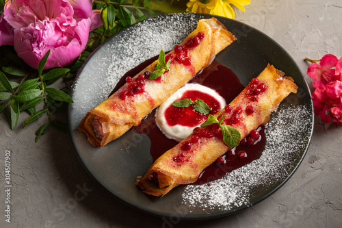 Foto pancakes stuffed with cottage cheese with sour cream and lingonberry sauce in a