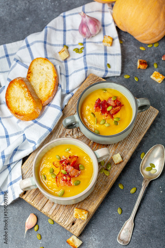 Homemade autumn hot pumpkin soup with bacon and seeds.