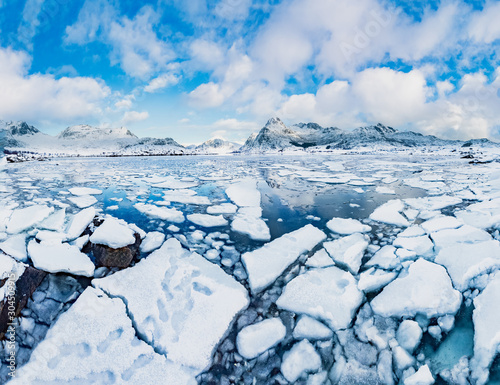 Amazign nature of Winter ladscape - Cracked blue ice in fjord on Lofoten Islands in Norway during snowy winter at picturesque mountains background. photo