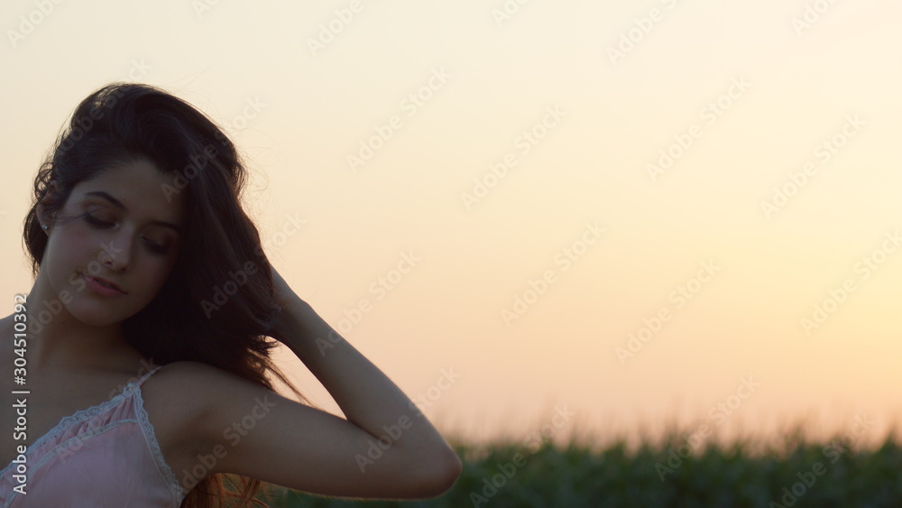 Beautiful woman standing staring at the camera at sunset Beautiful woman standing staring at the camera at sunset