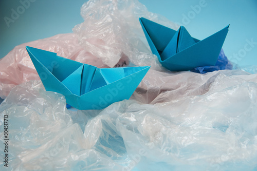 Ecology. The problem of pollution and debris in the ocean. Paper boats on plastic bags. Zero waste concept.
