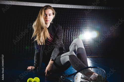 A portrait of a female tennis player with a racket posing in studio