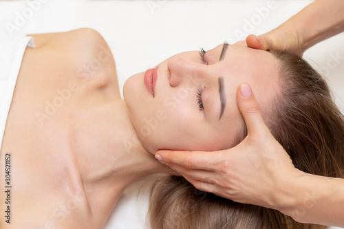 Young woman enjoying massage in spa salon. Face massage. Closeup of young woman getting spa massage treatment at beauty spa salon.Spa skin and body care. Facial beauty treatment.Cosmetology.