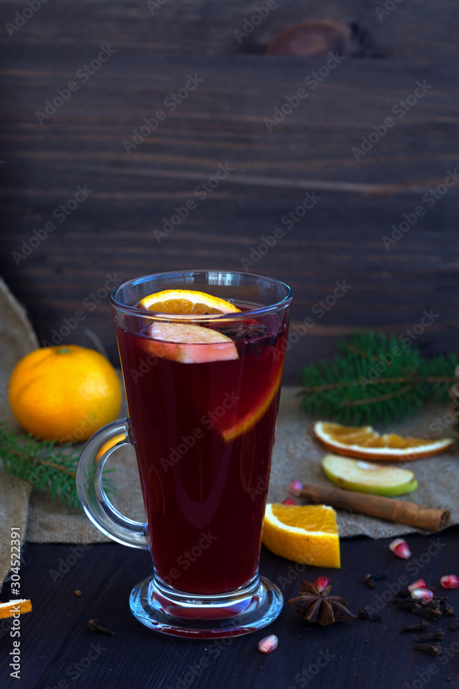 mulled wine with slices of orange, apple and spices, cinnamon and anise star on a wooden background with winter decorations. hot drinks of winter and autumn. vertical mulled wine with slices of orange, apple and spices, cinnamon and anise star on a wooden background with winter decorations. hot drinks of winter and autumn. vertical