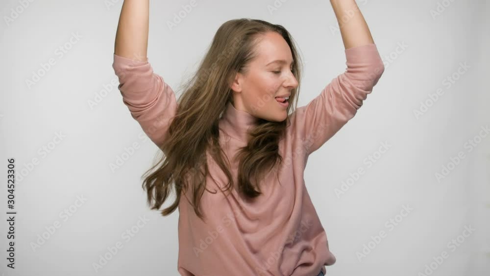Happy carefree brunette woman in pink blouse dancing over white background Happy carefree brunette woman in pink blouse dancing over white background