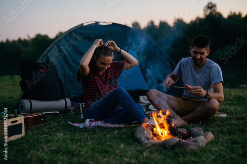 friends barbecue sausages on night camping outdoors