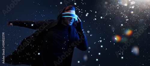 Young man having virtual reality experience. Guy using VR helmet. Augmented reality, future technology, game concept. Rainbow lights, flares.
