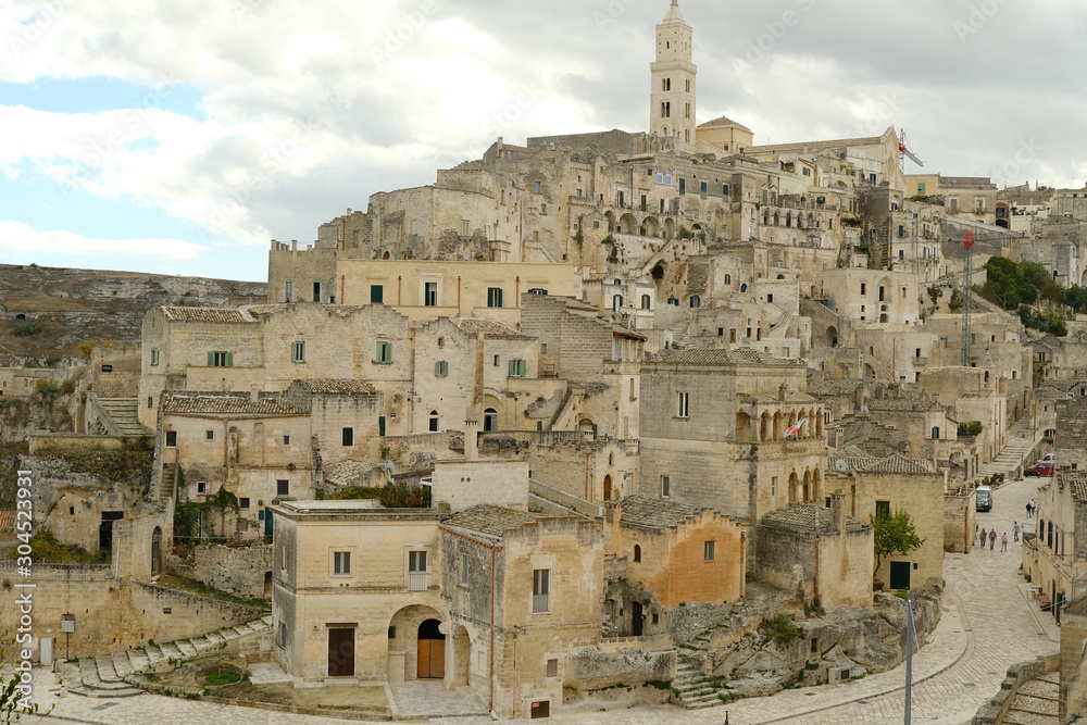 View of the city of Matera in Italy. Church with bell tower and houses built in beige tuff stone.