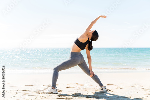 Woman Exercising While Stretching On Beach